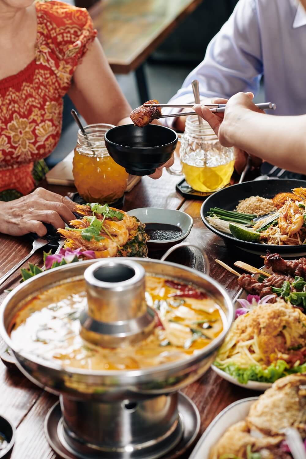 Group of people enjoying tasty dishes of Vietnamese cuisine during family dinner in restaurant